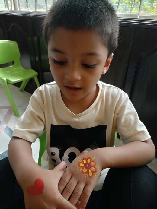 A child looking at a flower painted on their hand