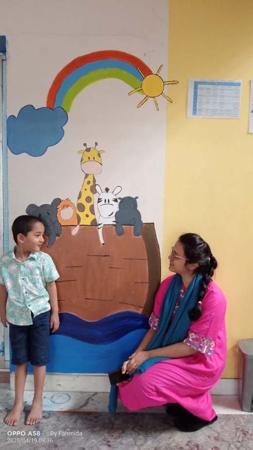 A child and therapist beside the Noah’s Ark wall mural