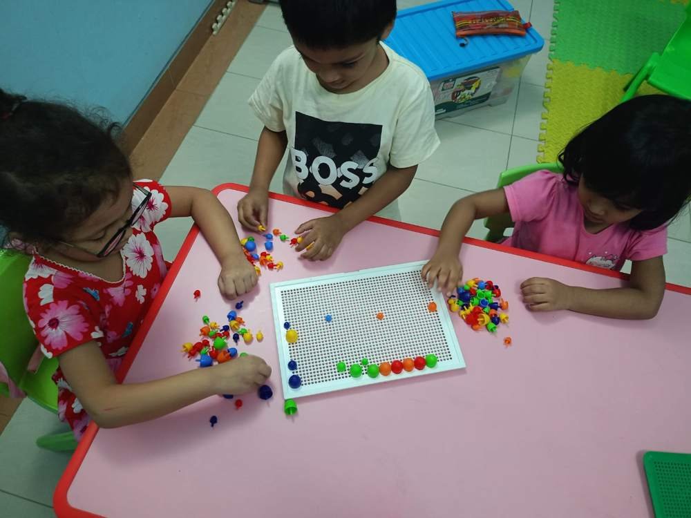 Children building a colourful pattern on a peg board