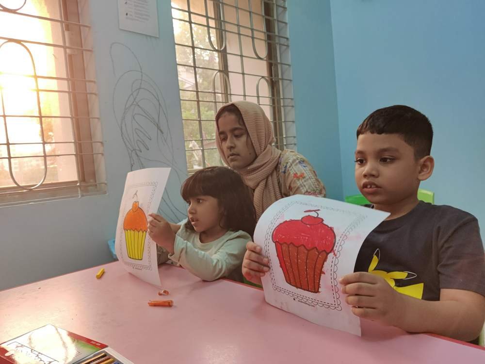 Children holding up their coloured cupcake pictures